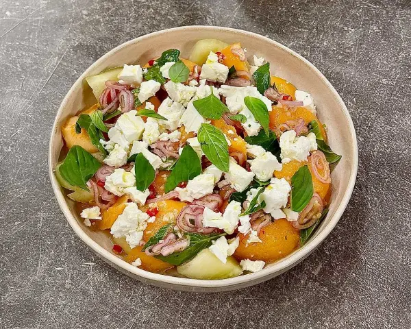 En uppfriskande melon och fetaostsallad med basilika och rödlök. Perfekt sommarbuffé.