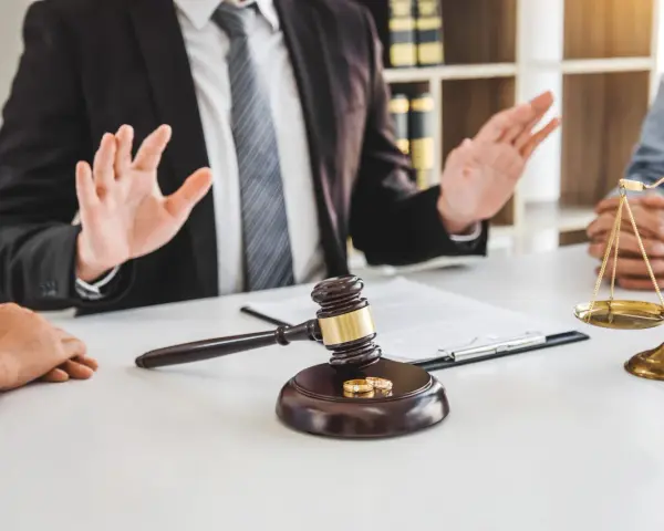 Un avocat explique les démarches pour un papier divorce mairie. Marteau de juge, alliances et balance de la justice sur la table.