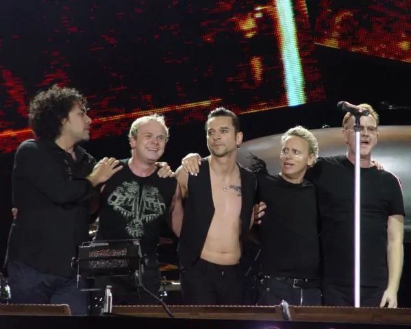 Les membres de Depeche Mode sur scène, souriants et complices, profitent de l'instant.