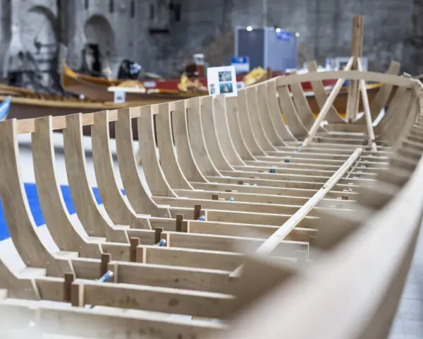 Struttura in legno di una barca veneziana in costruzione, con altre imbarcazioni sullo sfondo.