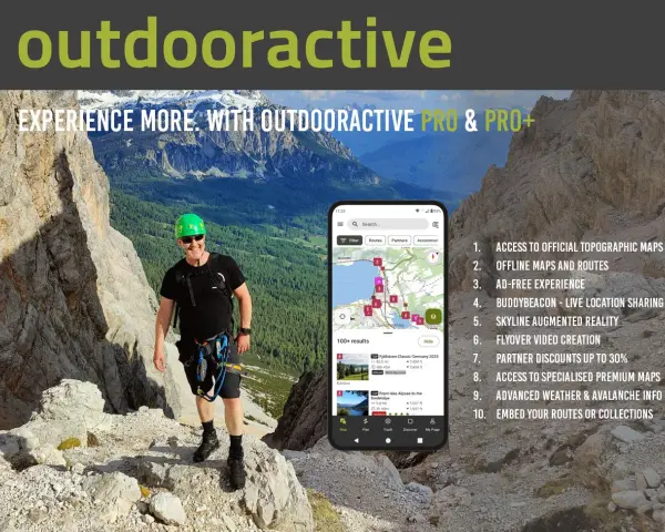Escursionista sorridente in montagna, con smartphone che mostra l'app outdooractive gratis con mappe e percorsi.