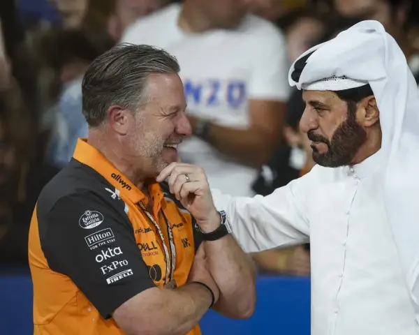 Mohammed Ben Sulayem, con túnica blanca, conversa animadamente con un hombre con polo naranja de McLaren.