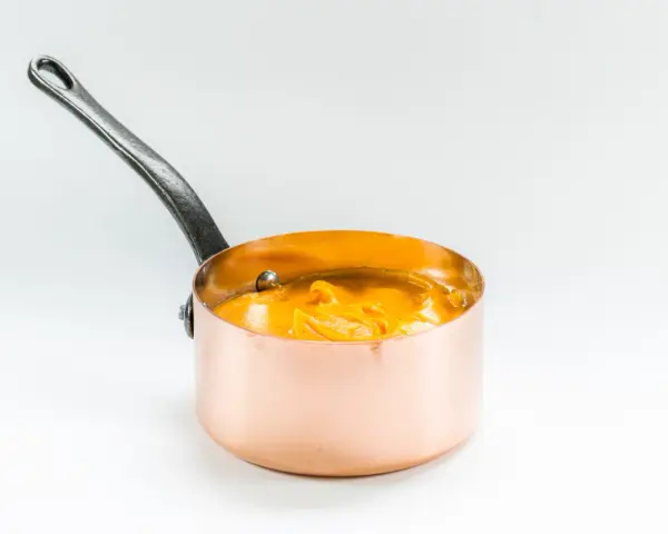 Cazo de cobre con puré de boniato cremoso y naranja, listo para servir.