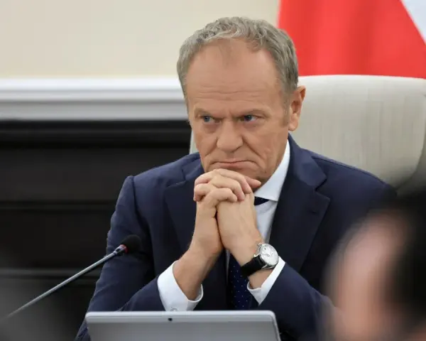 Mężczyzna w garniturze, z zaciętą miną, wygląda jak pesymista. Dłonie splecione, wzrok utkwiony w dal.