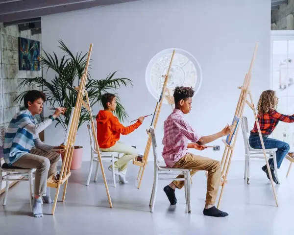 Des enfants concentrés sur leur peinture sur toile facile, créant des œuvres colorées dans un atelier lumineux.