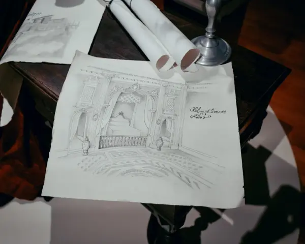 Szkice architektoniczne wnętrza, jakby z lekcji korepetycje z rysunku. Widać łóżko z baldachimem, balustradę i zdobioną podłogę.