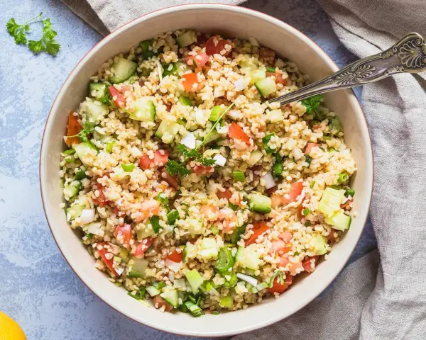 Frischer bulgur salat mit Tomaten, Gurken und Frühlingszwiebeln, garniert mit Petersilie.