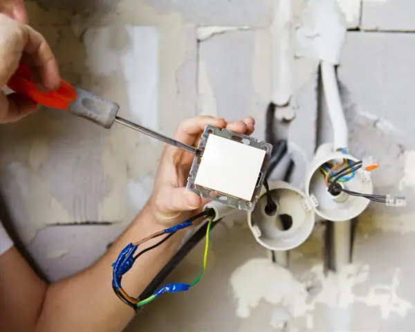 Elektryk montuje włącznik światła. Zastanawiasz się, ile kosztuje prąd budowlany?