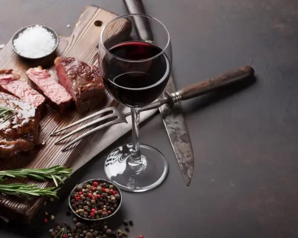 En saftig entrecote, perfekt tillagad, med ett glas rött vin. Kryddor och rosmarin fulländar upplevelsen.