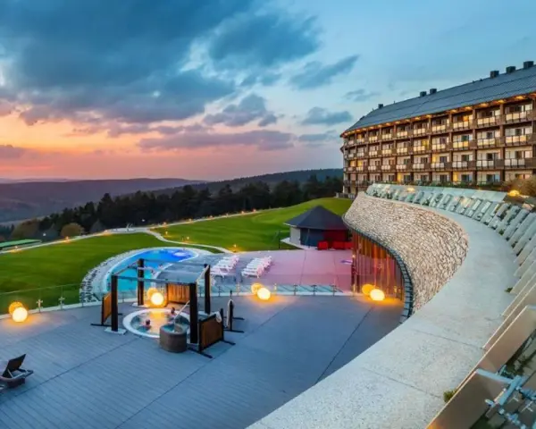 Widok na najbardziej luksusowy hotel w Polsce o zachodzie słońca, z basenem, jacuzzi i tarasem z leżakami.