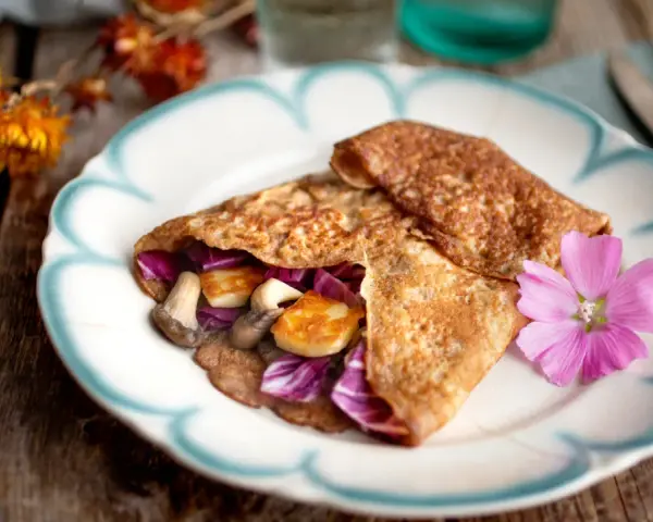 Matiga pannkakor fyllda med svamp, halloumi och rödkål, dekorerade med en rosa blomma.