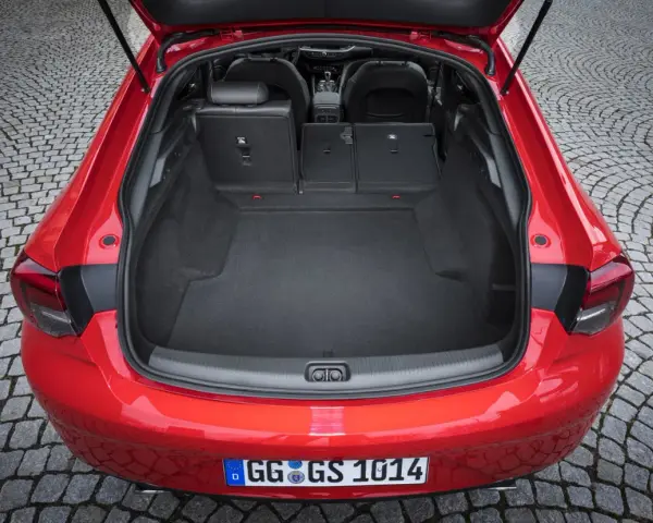 Czerwony Opel Insignia z otwartym bagażnikiem. Duża przestrzeń ładunkowa, idealna na wakacyjne wyjazdy. Sprawdź opel insignia pojemność bagażnika.