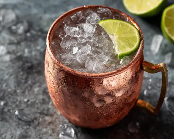 En iskall moscow mule i kopparmugg, garnerad med lime och omgiven av is.