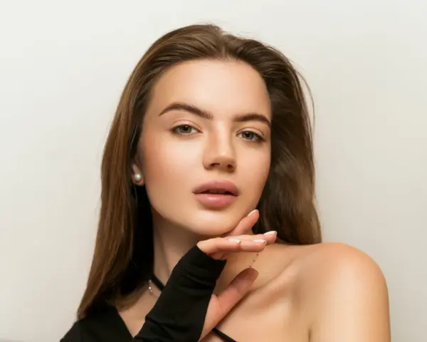 Delikatny makijaż nude podkreśla naturalne piękno młodej kobiety. Jej skóra lśni subtelnym blaskiem, a usta kuszą delikatnym kolorem.