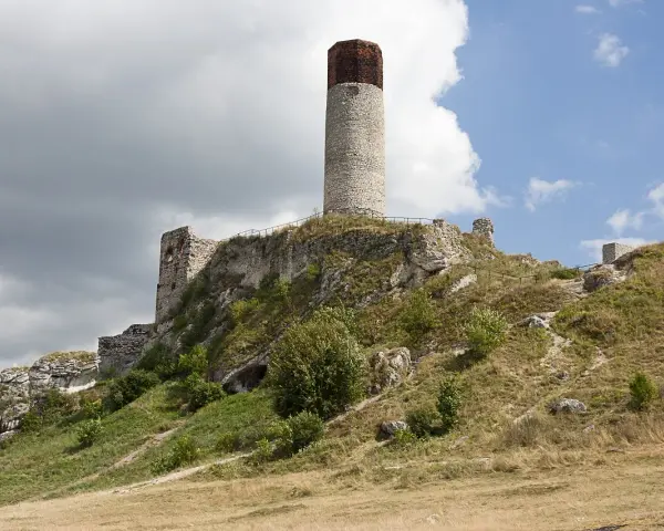 Ruiny zamku na wzgórzu, część Szlaku Orlich Gniazd. Charakterystyczna okrągła wieża i kamienne mury.