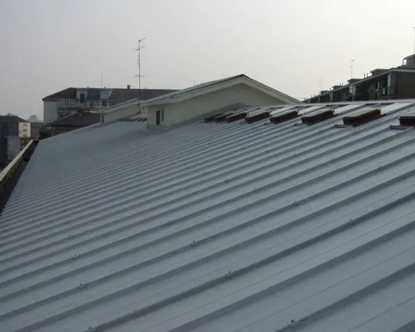 Tetto moderno rifatto con pannelli coibentati grigi, con lucernari a vista.