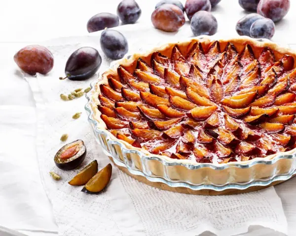 Une délicieuse tarte aux prunes, garnie de fruits frais et dorés, prête à être dégustée.