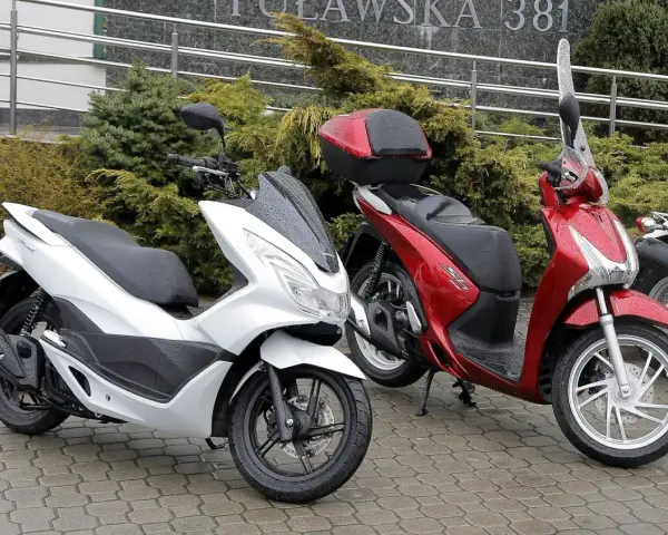Biały i czerwony skuter stoją na mokrym bruku. Zastanawiasz się, ile oleju do skutera 4t?