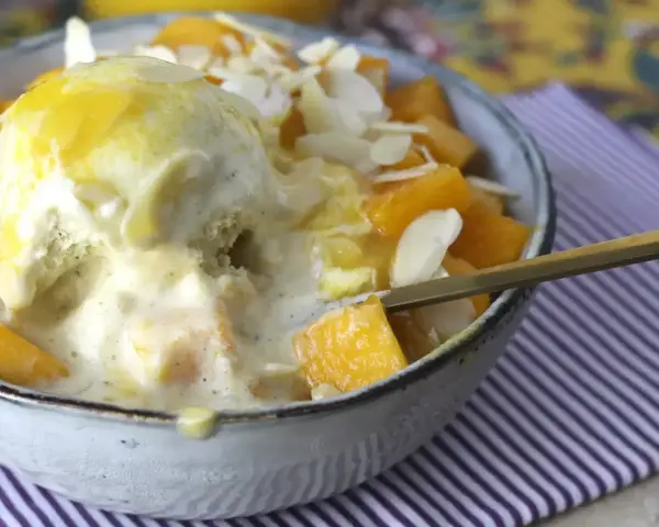 Pyszny deser Bingsu przepis: lody waniliowe z mango, płatkami migdałów i syropem.