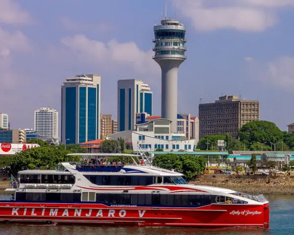 Prom na Zanzibar, "Kilimanjaro V", płynie przy nowoczesnej panoramie Dar es Salaam Tanzania, z charakterystyczną wieżą kontroli lotów.