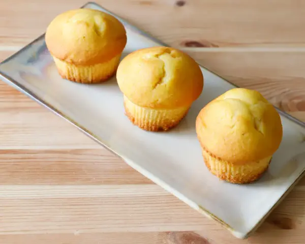 Tre soffici muffin allo yogurt dorati, pronti per essere gustati su un piatto rettangolare.
