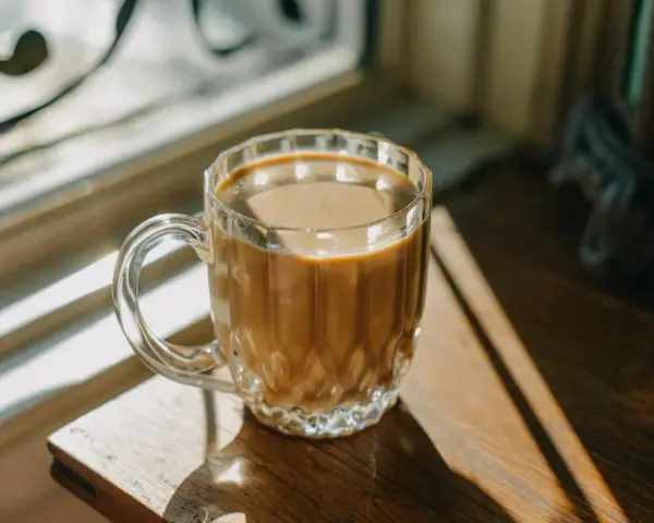 Kawa z mlekiem w szklance, oświetlona słońcem. Czy kawa z mlekiem jest zdrowa? To pytanie zadaje sobie wielu miłośników tego napoju.