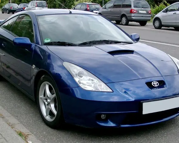 Błękitna Toyota Celica, jeden z najpiękniejszych aut, parkuje na poboczu drogi.