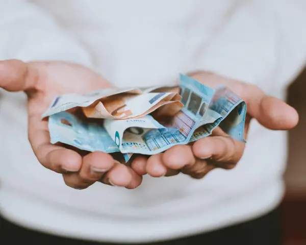 Dłonie trzymające banknoty euro, symbolizujące opłatę za pełnomocnictwo.