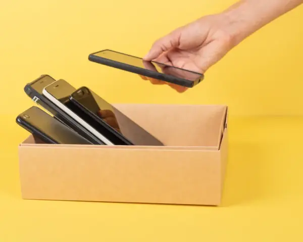 Ręka wkłada do kartonu kilka telefonów. Zastanawiam się, jaki mam model telefonu, bo wszystkie wyglądają podobnie.