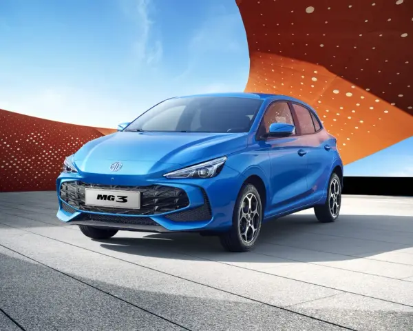 Niebieski MG3 Hybrid stoi na tle nowoczesnej architektury i błękitnego nieba.