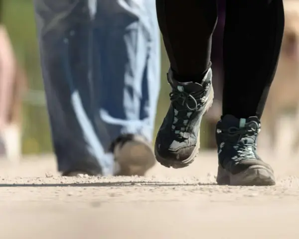 Wanderstiefel in Aktion, die den Boden aufwirbeln. Die boot geschwindigkeit ist spürbar, während die Wanderer voranschreiten.