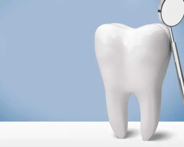 Biały ząb i lusterko dentystyczne. Pamiętaj, po piaskowaniu zębów nie wolno nic jeść przez godzinę.