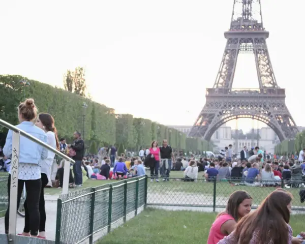 Gente disfrutando de un día soleado en París, con la Torre Eiffel de fondo. Un momento perfecto para la bise en France.