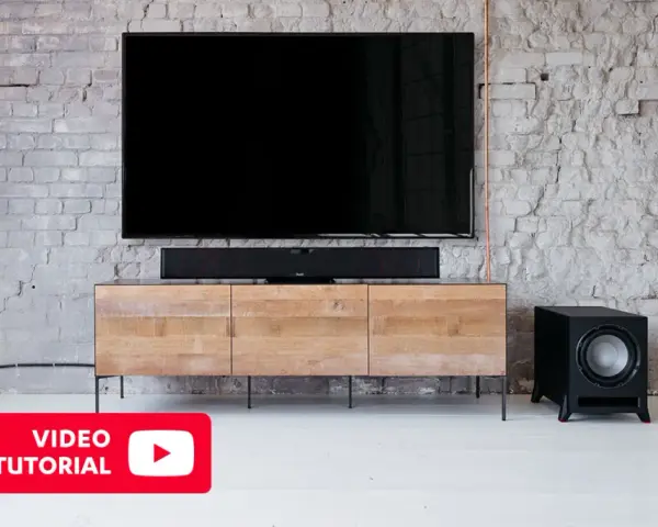 Schwarzer Subwoofer neben einem TV-Möbel. Hier erfahren Sie mehr über den subwoofer anschluss.