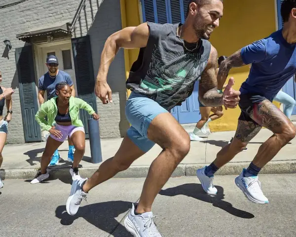 Grupa biegaczy w letnich strojach pokonuje miejską trasę. To inspiracja, jak przygotować się do maratonu, czerpiąc radość z ruchu.