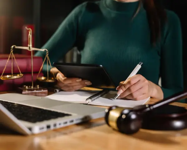 Prawniczka analizuje dokumenty, pilnując, by nie przegapić ostatniego przedawnienia długu. Na biurku waga sprawiedliwości, laptop i młotek sędziowski.