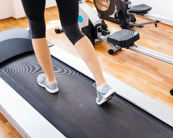 Gambe di donna che cammina su un tapirulan, in allenamento per la gravidanza.