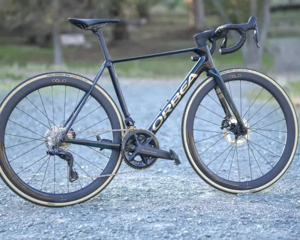 A dark blue Orbea Orca road bike with gold lettering, Ultegra components, and deep-dish wheels. This is a great bike for an Orbea Orca review.