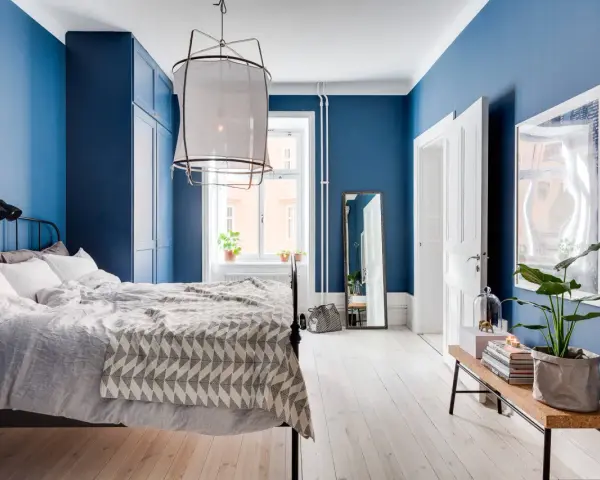 Accogliente camera da letto blu con letto comodo, armadio scuro e specchio a figura intera.