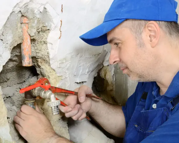 Klempner repariert Wasserhahn. Ein Rohrbruch, für den die Versicherung nicht zahlt, ist eine teure Angelegenheit.