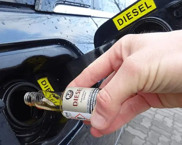 Dłoń wlewa dodatek do benzyny do baku samochodu z napisem DIESEL.