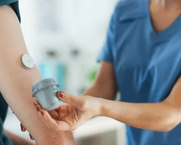 Lekarz od chorób metabolicznych pomaga pacjentowi z glukometrem na ramieniu.