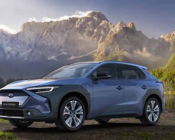 Niebieski Subaru Solterra stoi nad jeziorem z górami w tle.