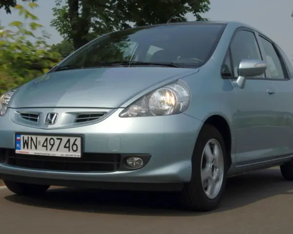 Jasnoniebieski Honda Jazz 2 na drodze, z zielenią w tle.