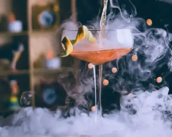 Elegancki drink z pomarańczową skórką, otoczony mgłą, idealny do nauki, jak pić bourbon.