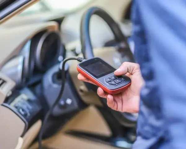 Diagnostyka Renault, być może błąd DTC B1267. Ręka trzyma urządzenie diagnostyczne podłączone do samochodu.