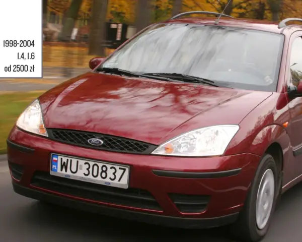 Czerwony Ford Focus Mk1 1.6 benzyna z lat 1998-2004, poruszający się po drodze.