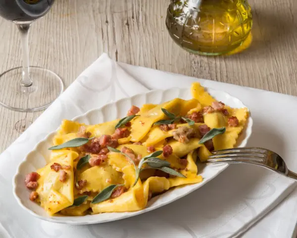 Piatto di casoncelli alla bergamasca conditi con burro, salvia e pancetta croccante.