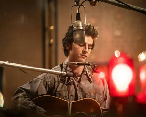 Un jeune homme à la guitare et à l'harmonica, dans un style de musique rappelant Bob Dylan, enregistre en studio.