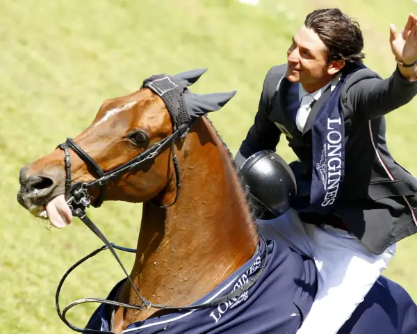 Un cavalier, Nino des Buissonnets, salue la foule depuis son cheval après une compétition.